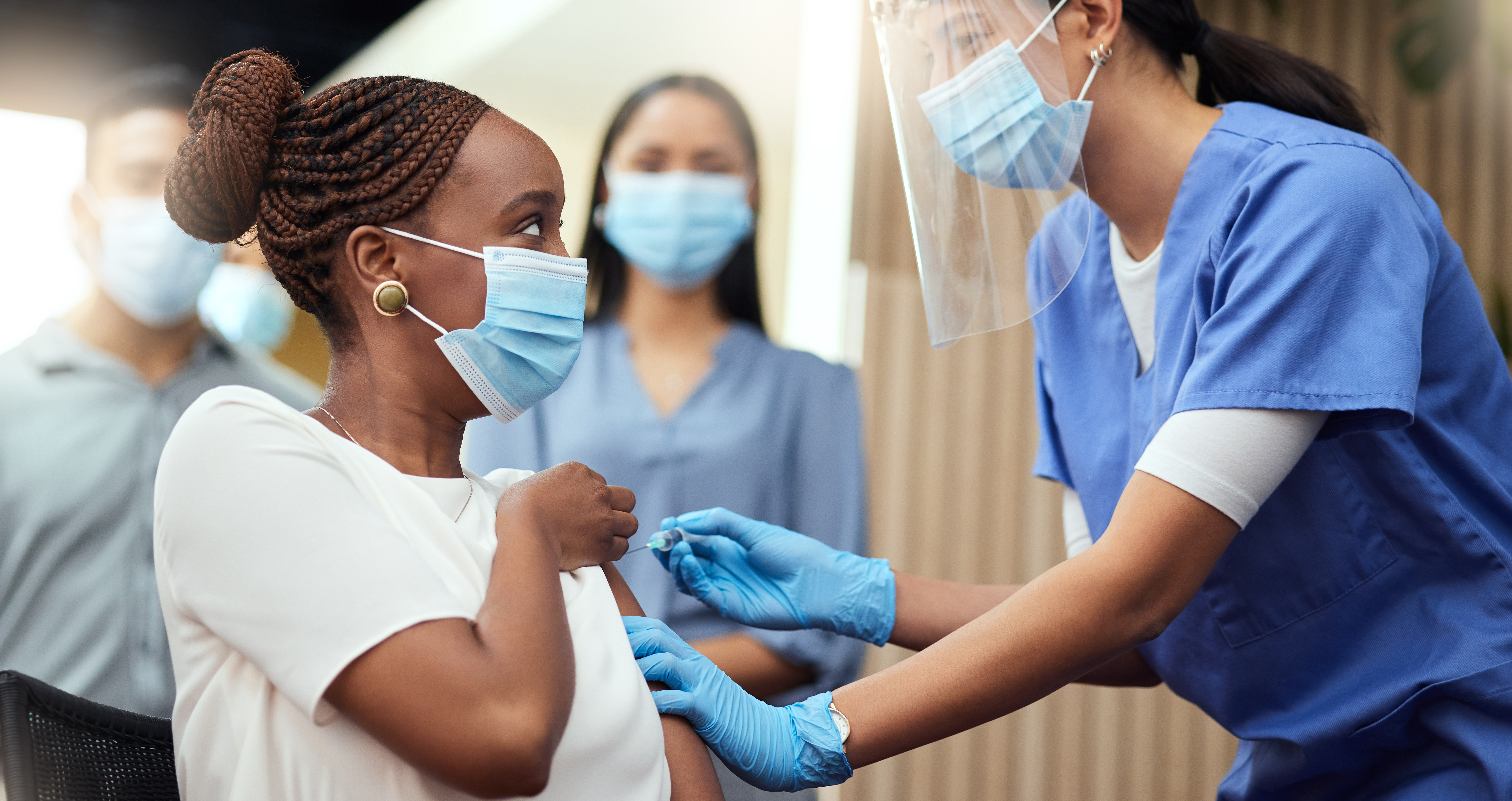 girl taking a vaccine and surrounded by nurses